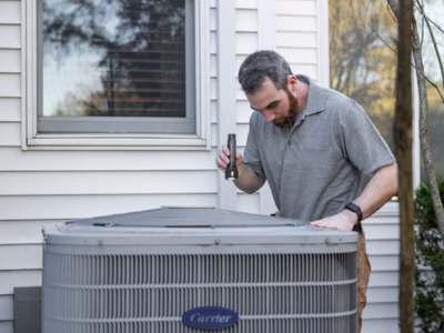 Technician inspecting outdoor hvac unit.
